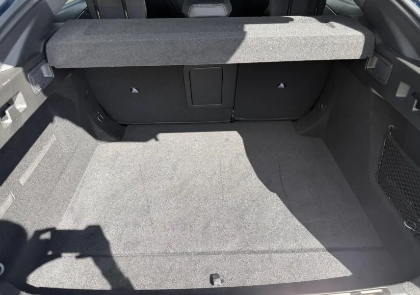 Vue du coffre spacieux de la Peugeot 408 Hybrid 145ch GT, intérieur noir avec cache-bagages relevé.