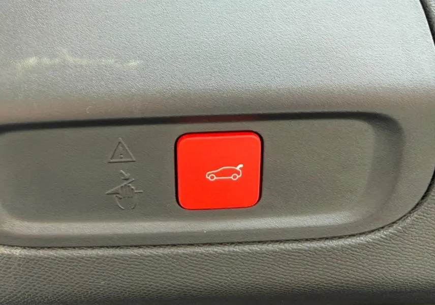 Bouton rouge d'ouverture électrique du coffre sur tableau de bord intérieur d'une Peugeot 408 Bleu Obsession.