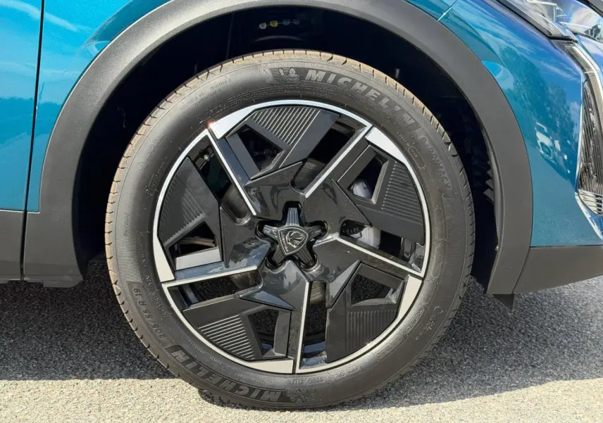 Gros plan sur la roue avant droite avec jante alu noire et argentée du Peugeot 408 Hybrid Bleu Obsession.