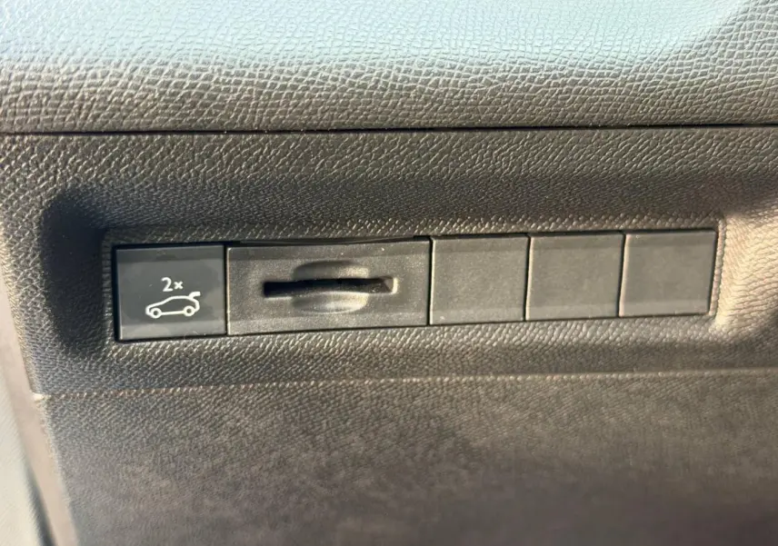Bouton d'ouverture électrique du coffre sur tableau de bord noir du Peugeot 408 Hybrid 2025.