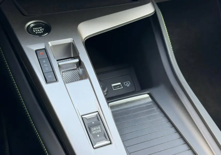 Vue rapprochée de la console centrale argentée avec sélecteur de mode de conduite et bouton start du Peugeot 408 Hybrid 2025.