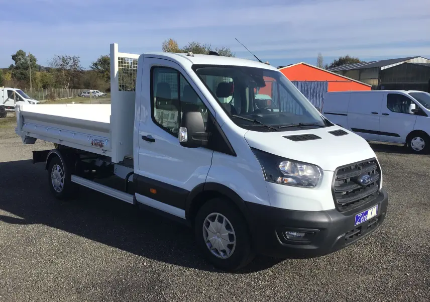 Ford Transit Chassis Cabine blanc vu en 3/4 avant droit avec benne arrière et bras polybenne sur parking extérieur.