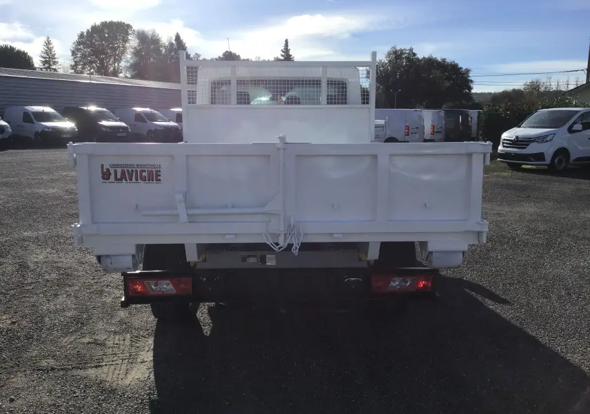 Vue arrière d'un Ford Transit Châssis Cabine blanc avec benne 3m20 et grillage protecteur de cabine.