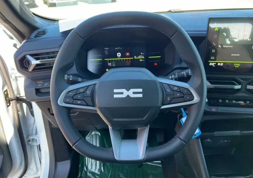Vue centrée sur le volant du Dacia Bigster blanc glacier 2025, avec tableau de bord numérique et écran tactile visible.