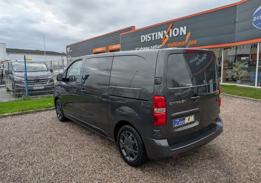 Vue 3/4 arrière droite d'un Citroën Jumpy gris avec vitres latérales surteintées et boucliers couleur carrosserie.