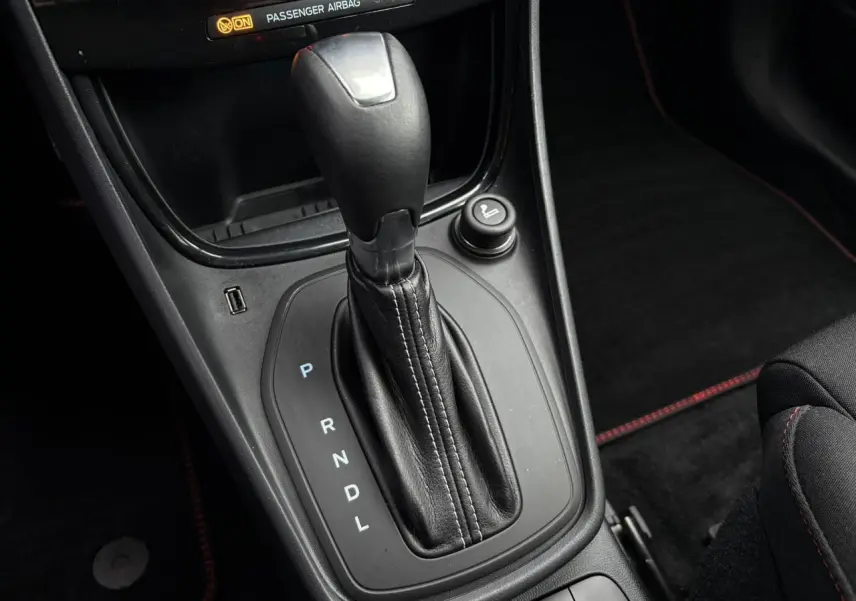 Gros plan sur la console centrale noire du Ford Puma 2023 avec levier de vitesse automatique et coutures rouges visibles.