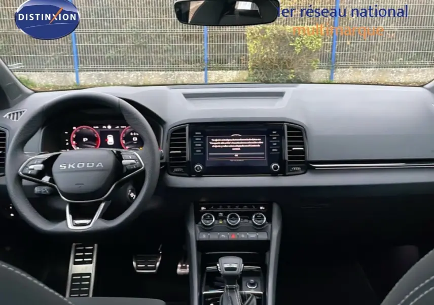 Vue intérieure frontale du tableau de bord noir du Skoda Karoq 2025 avec volant multifonction et écran central tactile.