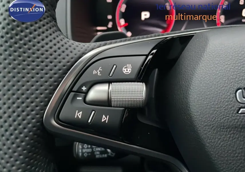 Gros plan sur les commandes multifonctions du volant noir perforé du Skoda Karoq gris argent 2025, avec molette métallique.