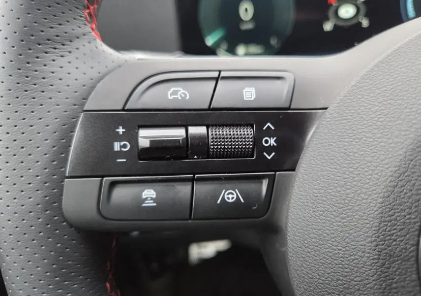 Gros plan sur les commandes gauche du volant cuir perforé avec surpiqûres rouges du Hyundai Tucson N Line gris métallisé.