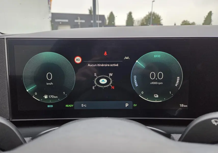 Vue intérieure du tableau de bord numérique du Hyundai Tucson gris, affichant vitesse, RPM et navigation.
