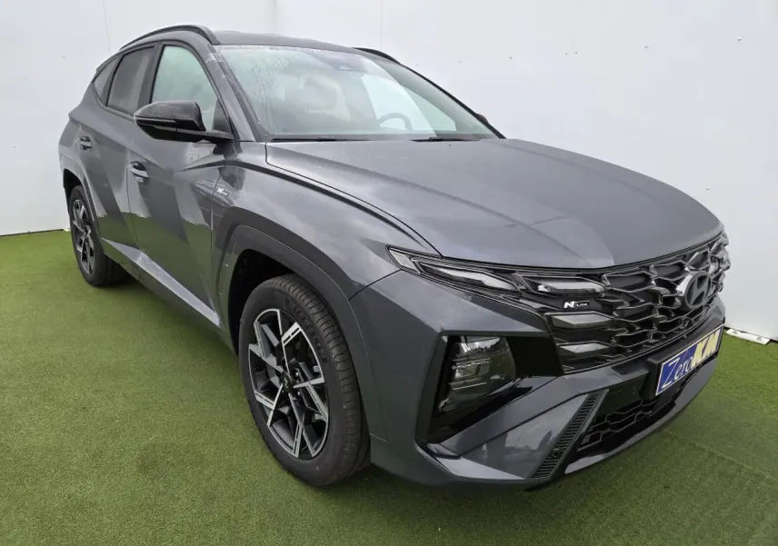 Vue 3/4 avant gauche du Hyundai Tucson 2025 gris métallisé Ecotronic avec calandre N Line et jantes alliage 19 pouces.