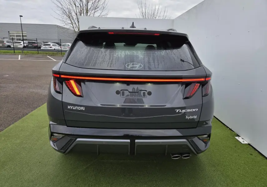 Vue arrière du Hyundai Tucson 2025 gris métallisé avec feux LED allumés et double sortie d’échappement côté droit.