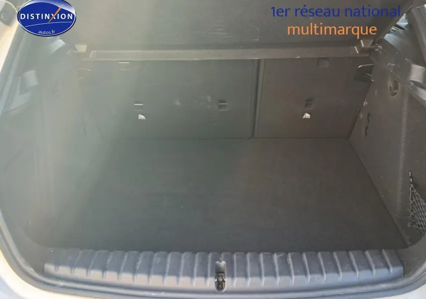 Coffre ouvert vu de l'arrière d'une BMW Série 1 blanche, montrant un espace de chargement propre et vide.