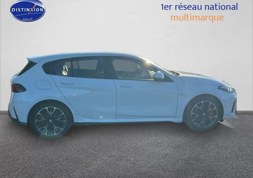 Profil droit d'une BMW Série 1 blanche alpin avec jantes 18 pouces bicolores en Y, sur fond clair intérieur showroom.