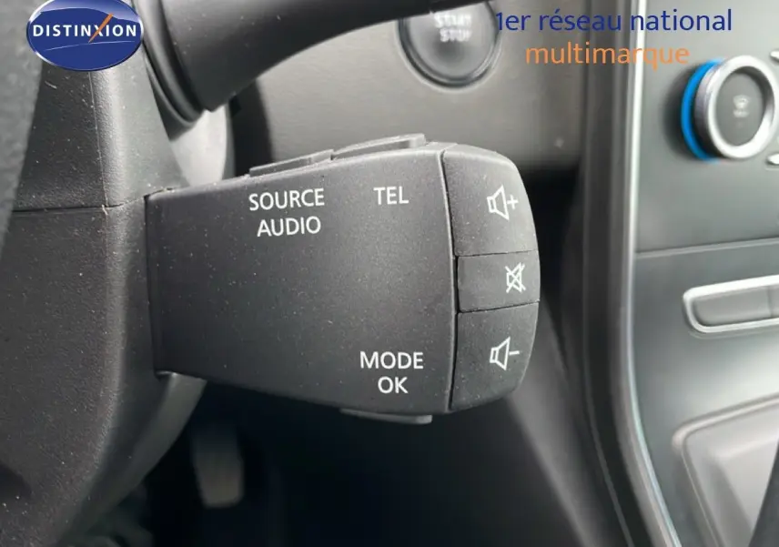 Gros plan sur la commande audio au volant d’un Renault Grand Scenic noir étoile métal, avec bouton mode et volume.