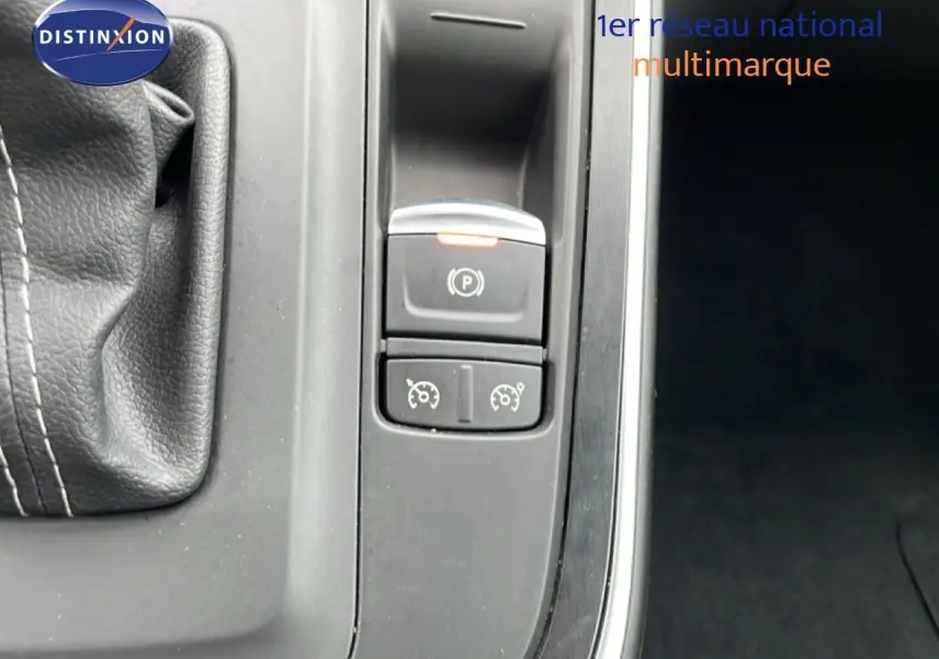 Gros plan sur la console centrale du Renault Grand Scenic noir étoile métal, montrant le frein à main électronique et commandes de régulateur.