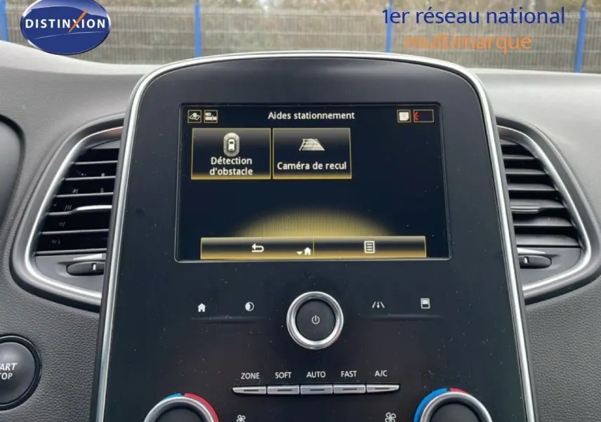 Vue rapprochée du tableau de bord noir du Renault Grand Scenic 2022, écran tactile affichant les aides au stationnement.