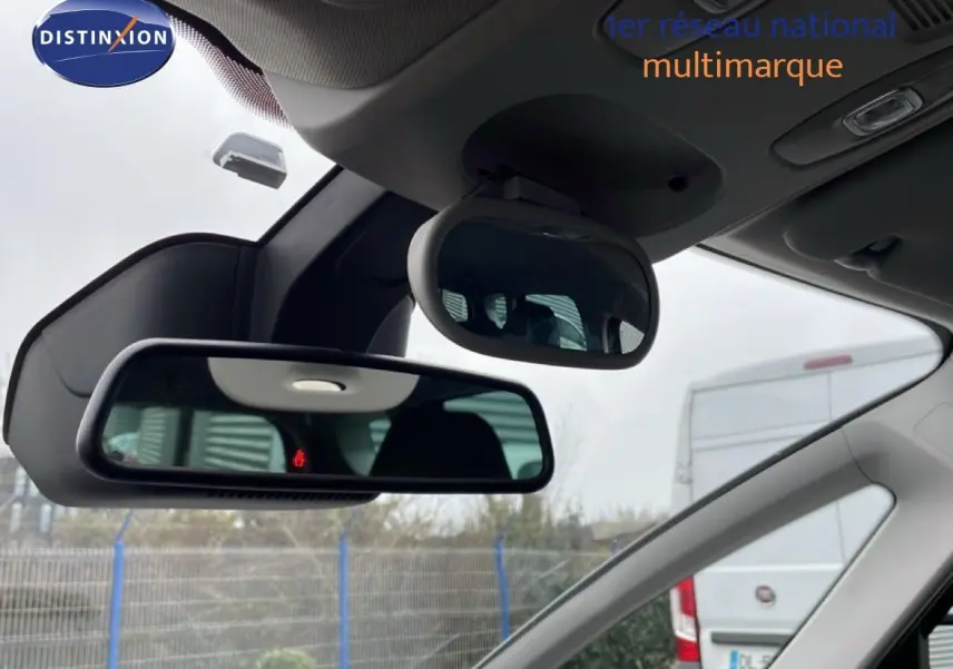 Vue intérieure du rétroviseur central et miroir enfant du Renault Grand Scenic noir étoile métal, avec arrière-plan extérieur flou.