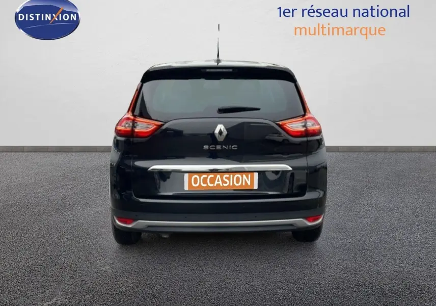 Vue arrière d’un Renault Grand Scenic noir étoile métal avec logo et feux arrière allumés sur fond neutre.