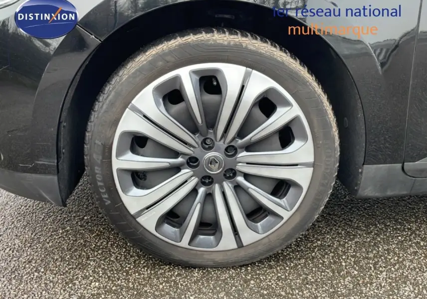 Gros plan sur la roue avant gauche du Renault Grand Scenic noir étoile métal, mettant en valeur la jante alu distinctive.