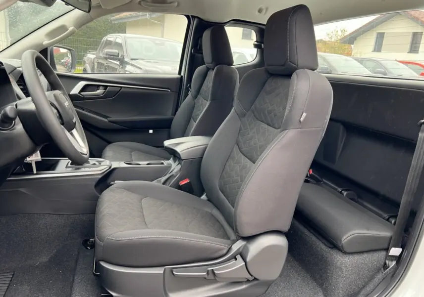 Vue intérieure côté gauche du pick-up Isuzu D-MAX 2026 Splash white, sièges tissu gris avec accoudoir central avant.
