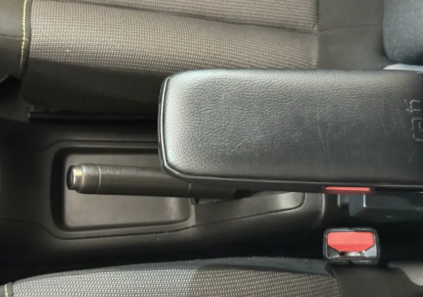 Vue rapprochée de la console centrale intérieure de la Citroën C3 blanche, avec frein à main et accoudoir noir.