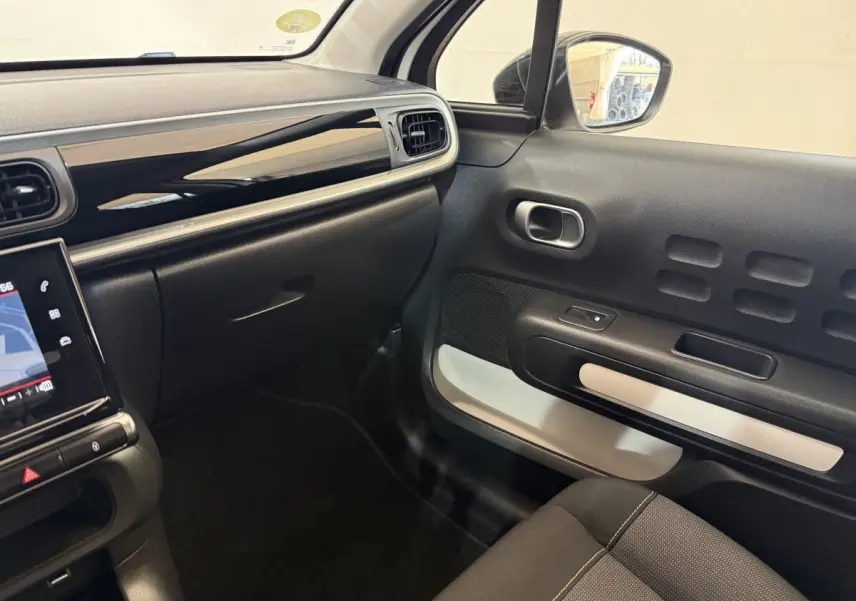 Vue intérieure côté passager de la Citroën C3 blanche 2021, avec tableau de bord noir brillant et détails modernes.