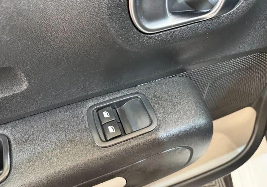 Gros plan sur les commandes des vitres électriques côté conducteur d'une Citroën C3 blanche, intérieur noir.