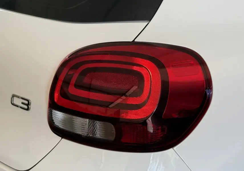 Gros plan sur le feu arrière droit rouge et blanc d'une Citroën C3 blanche, avec le logo C3 visible sur la carrosserie.