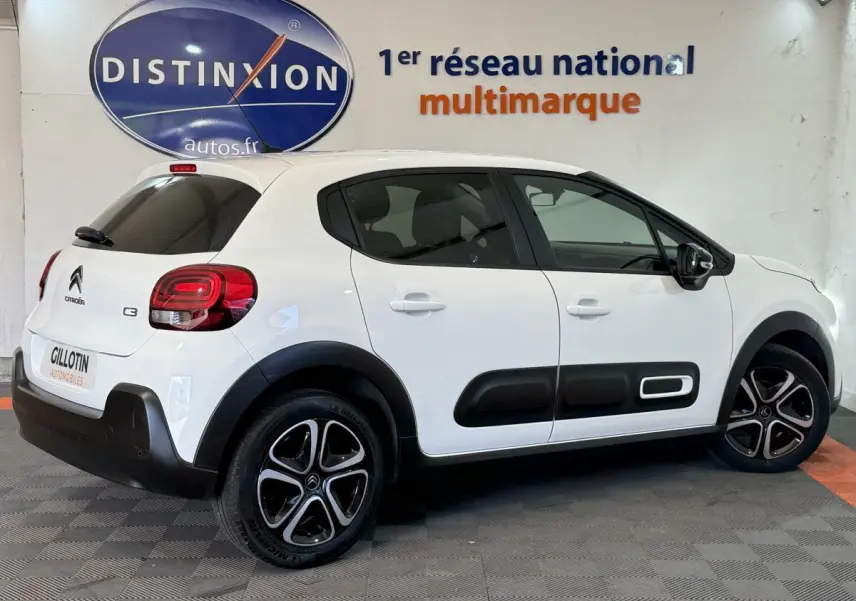 Citroën C3 blanc vue de côté droit en intérieur, avec protections latérales noires et jantes alliage distinctives.