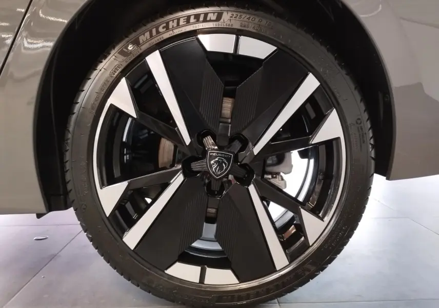Gros plan sur la jante alliage bi-ton noir et argent avec logo Peugeot sur un pneu Michelin, partie avant droite gris selenium.