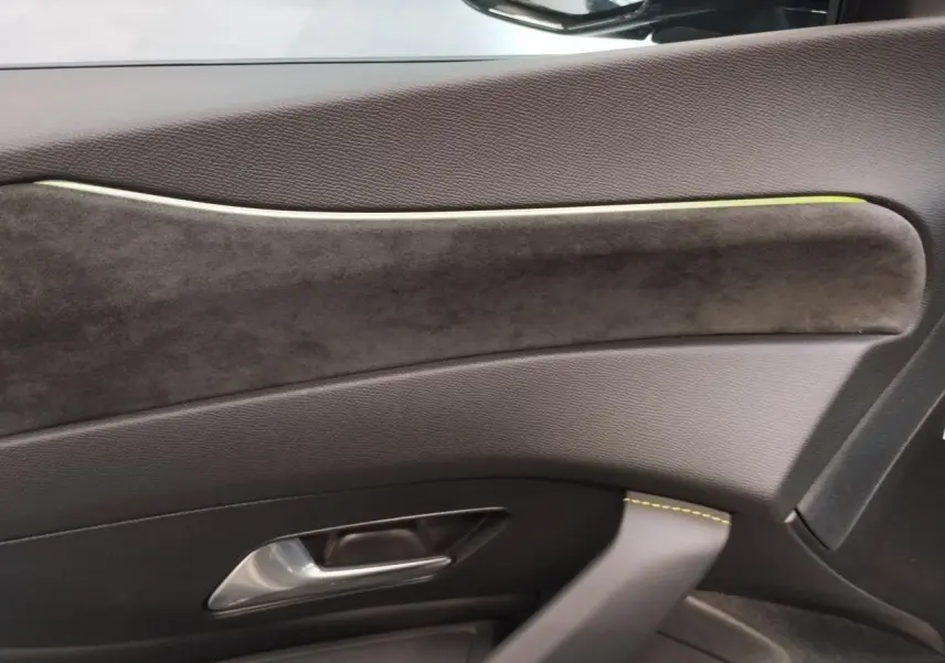 Gros plan sur la garniture intérieure de porte côté droit du Peugeot 308 gris Selenium avec surpiqûres vert Adamite.
