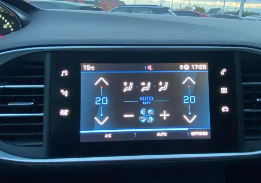 Écran tactile central affichant la climatisation automatique bi-zone dans une Peugeot 308 gris clair, vue intérieure frontale.