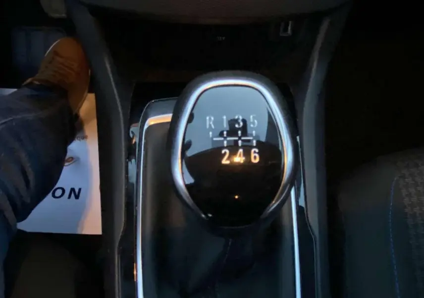 Gros plan sur le levier de vitesse manuel de la Peugeot 308 gris clair, avec indications des 6 rapports et marche arrière.