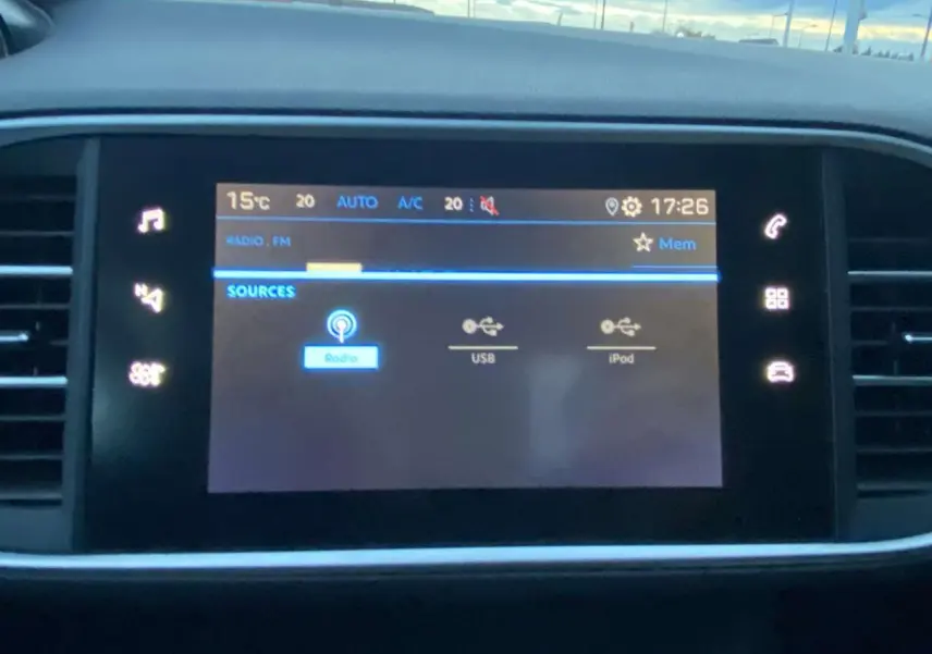 Écran tactile central de la Peugeot 308 2020 affichant les sources audio avec commandes lumineuses autour.