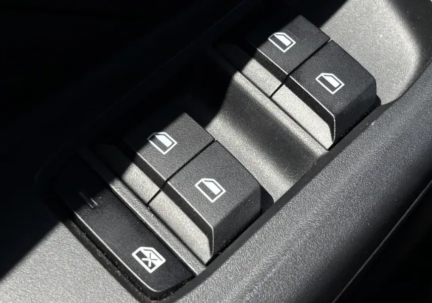 Gros plan sur les boutons de commande des vitres électriques côté conducteur du MG3 blanc Dover 2025.