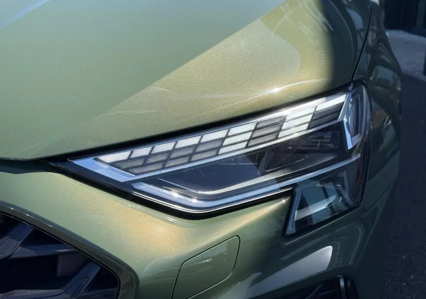 Gros plan sur le phare avant droit de l'Audi A3 Sportback 40 TFSI e vert District métallisé, soulignant ses détails LED.