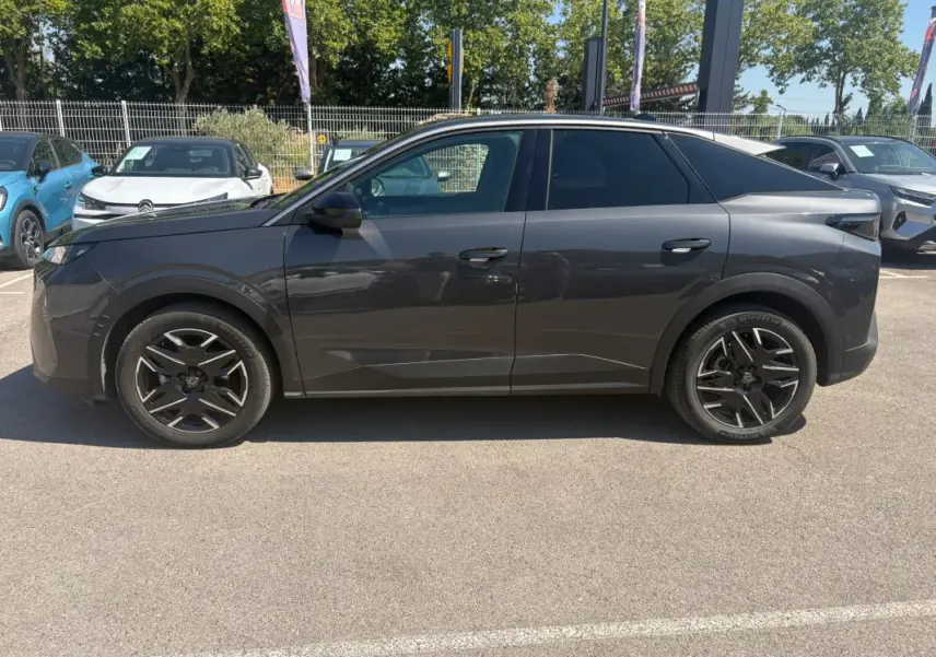 Vue de profil côté gauche d’un Peugeot 3008 Hybrid gris avec jantes alliage 18 pouces sur parking extérieur.