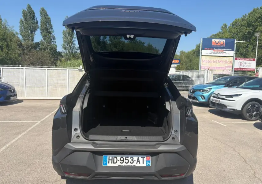 Vue arrière d'un Peugeot 3008 gris 2025 avec coffre ouvert, jantes alliage 18 pouces visibles au soleil.