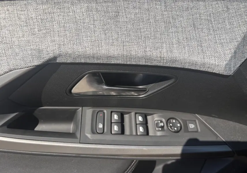 Vue du panneau de porte côté conducteur du Peugeot 3008 gris, avec commandes des vitres et rétroviseurs.