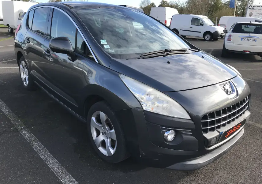 Peugeot 3008 gris anthracite vue 3/4 avant droit sur parking, avec calandre et phares distinctifs visibles.