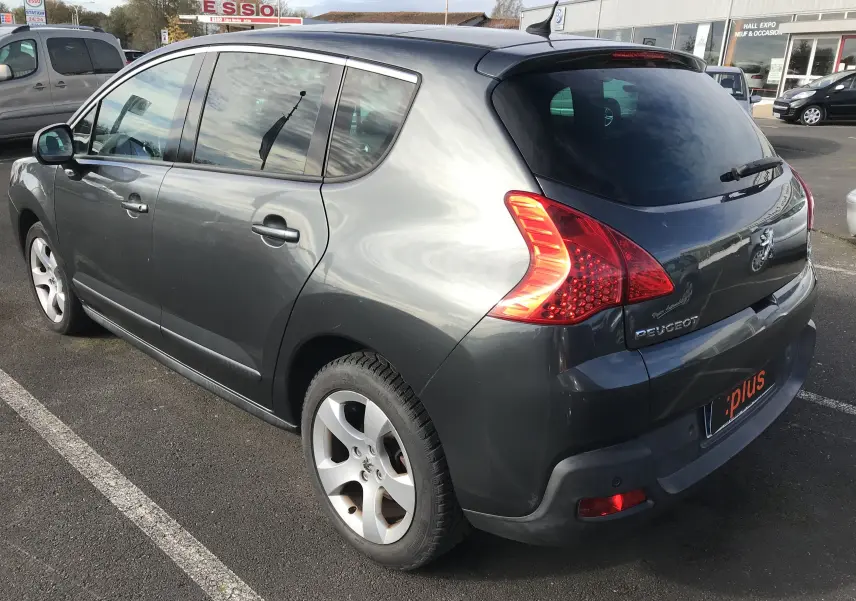 Vue 3/4 arrière droite d'un Peugeot 3008 gris anthracite 2011 avec feux arrière caractéristiques et jantes alliage.