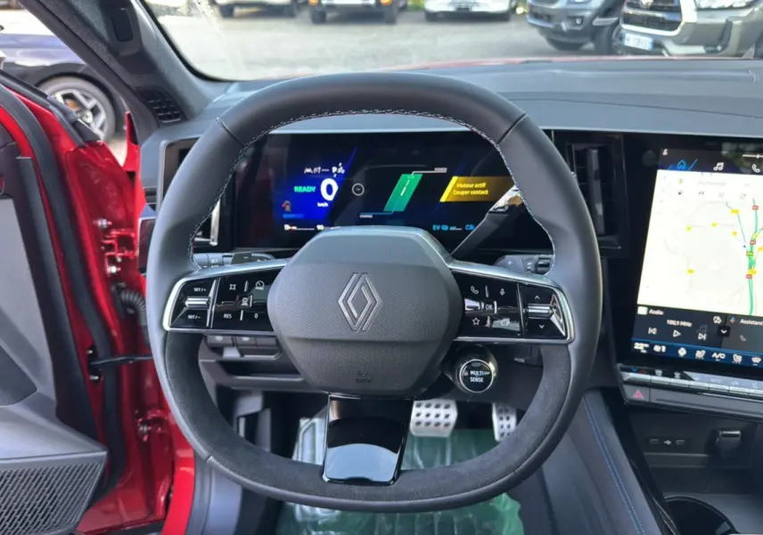 Vue intérieure centrée sur le volant du Renault Austral 2025 rouge toit noir, avec tableau de bord numérique et écran tactile.
