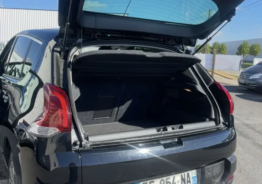 Vue arrière ouverte d'un Peugeot 3008 noir 2016 avec hayon relevé et attelage visible sur parking extérieur.
