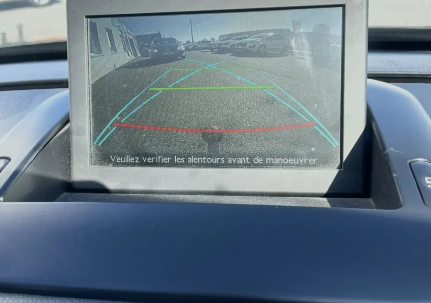 Écran de caméra de recul du Peugeot 3008 noir, affichant les lignes d’aide au stationnement arrière en extérieur.