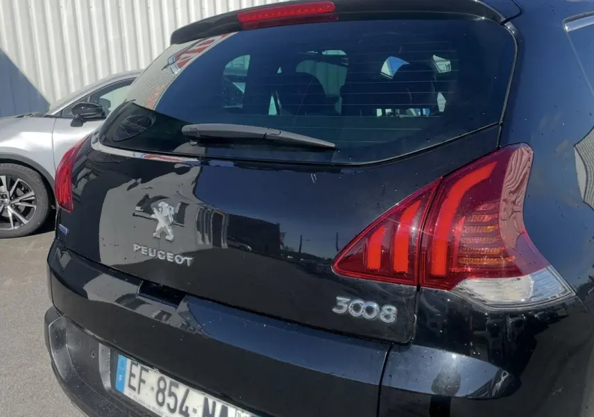 Vue 3/4 arrière droite d'un Peugeot 3008 noir 2016 avec attelage et feux arrière distinctifs au soleil.