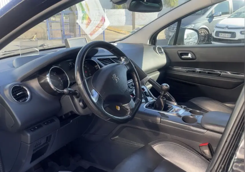 Intérieur noir du Peugeot 3008 2016 vu côté conducteur, volant cuir, levier de vitesses manuel et sièges en cuir.