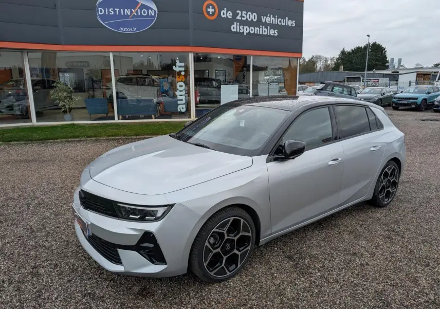 Opel Astra 2024 gris métallisé vue 3/4 avant avec toit noir et jantes alliage pentagonales diamantées.