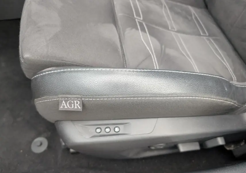 Gros plan sur le siège conducteur gris mixte Alcantara et cuir de l'Opel Astra 2024 avec label AGR et commandes électriques.