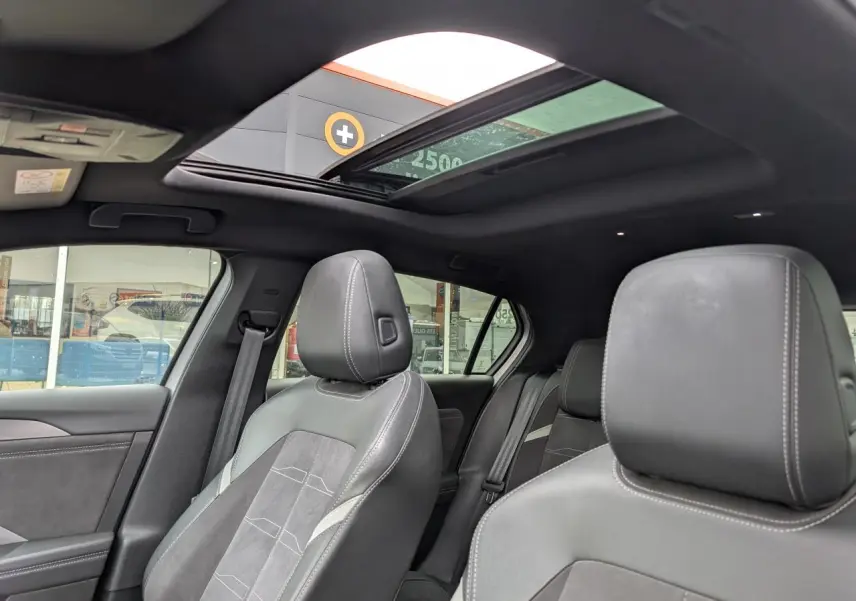 Vue intérieure montrant les sièges avant en sellerie mixte gris et toit ouvrant panoramique de l'Opel Astra 2024.